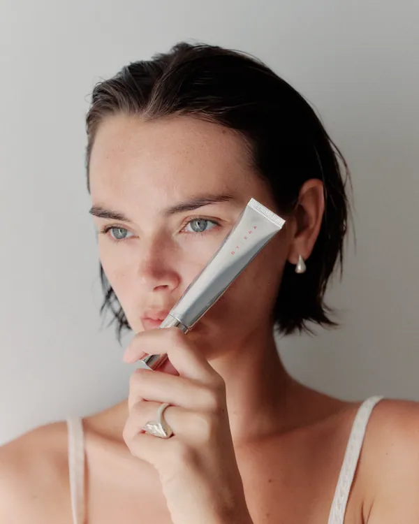 Alexandra Hawley holding a BY:ERA tube to her face — BY:ERA skincare campaign
